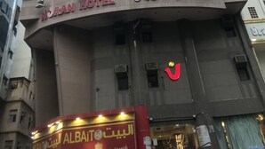 Een hotel met meerdere verdiepingen, balkons en een bord waarop staat Noran Hotel.