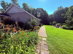 A house with a paved pathway leading to a grassy yard.