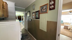 Um corredor com geladeira, relógio e quadros nas paredes.