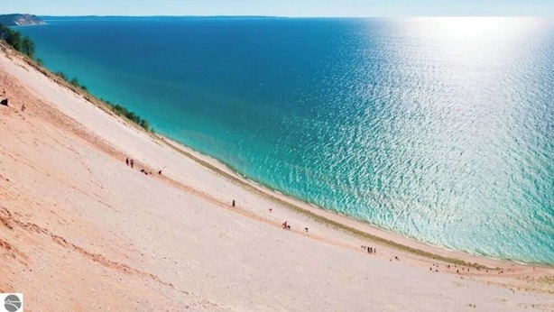 Uma praia com vista clara do oceano e um declive arenoso.