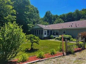 A two-story house with a well-maintained lawn and a small garden area.