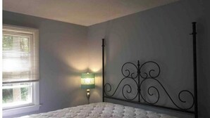 Une chambre à coucher avec un lit à baldaquin, une fenêtre avec des stores et une lampe fixée au mur.
