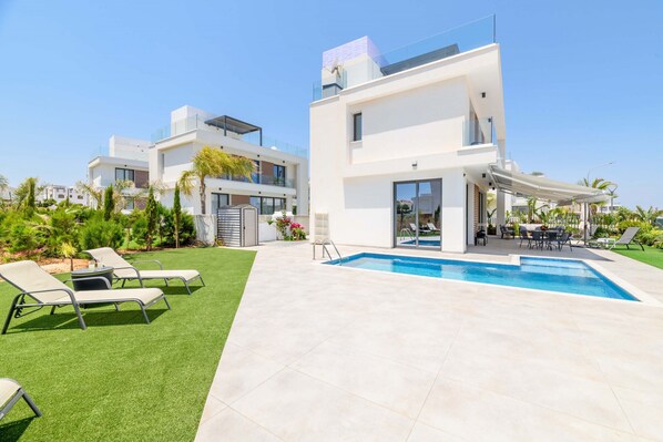A modern two-story house with a swimming pool, outdoor seating, and a well-maintained lawn. - By The Beach - Emerald Seaview Villa - Stunning Seaview Stay (Protaras)