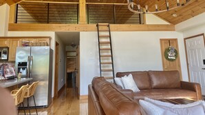 Un loft espacioso con techo alto, cocina moderna, sofá de cuero y una araña.