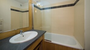Bathroom features a large mirror, sink with single faucet, and a bathtub.
