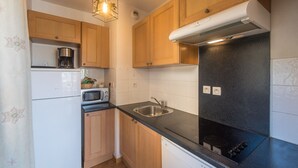 A compact kitchen with wooden cabinets, a microwave, a coffee maker, and a black countertop. - Apt 8 ppl, balcony, near the ski runs, parking (Orcières)