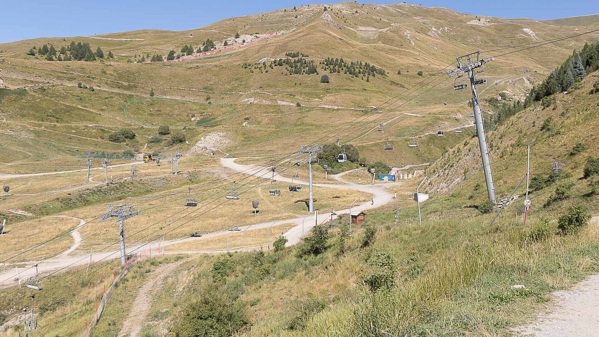 A mountainous area with a ski lift and a dirt path.