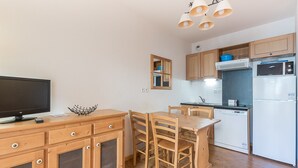 A compact kitchen with wooden cabinets, a built-in microwave, and a refrigerator. - Bright apt 4 ppl near the ski runs, balcony (Orcières)