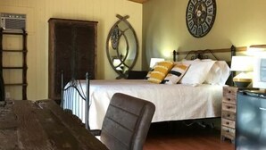 A room with a wooden ceiling, a bed with white bedding, a wooden desk, and a chair. - auberge maison gagne (Tadoussac)