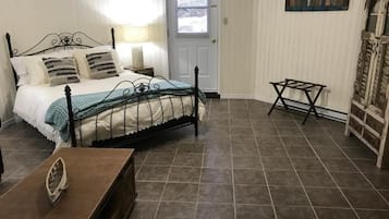 Un dormitorio con cama, mesitas de noche, banco de madera y armario.