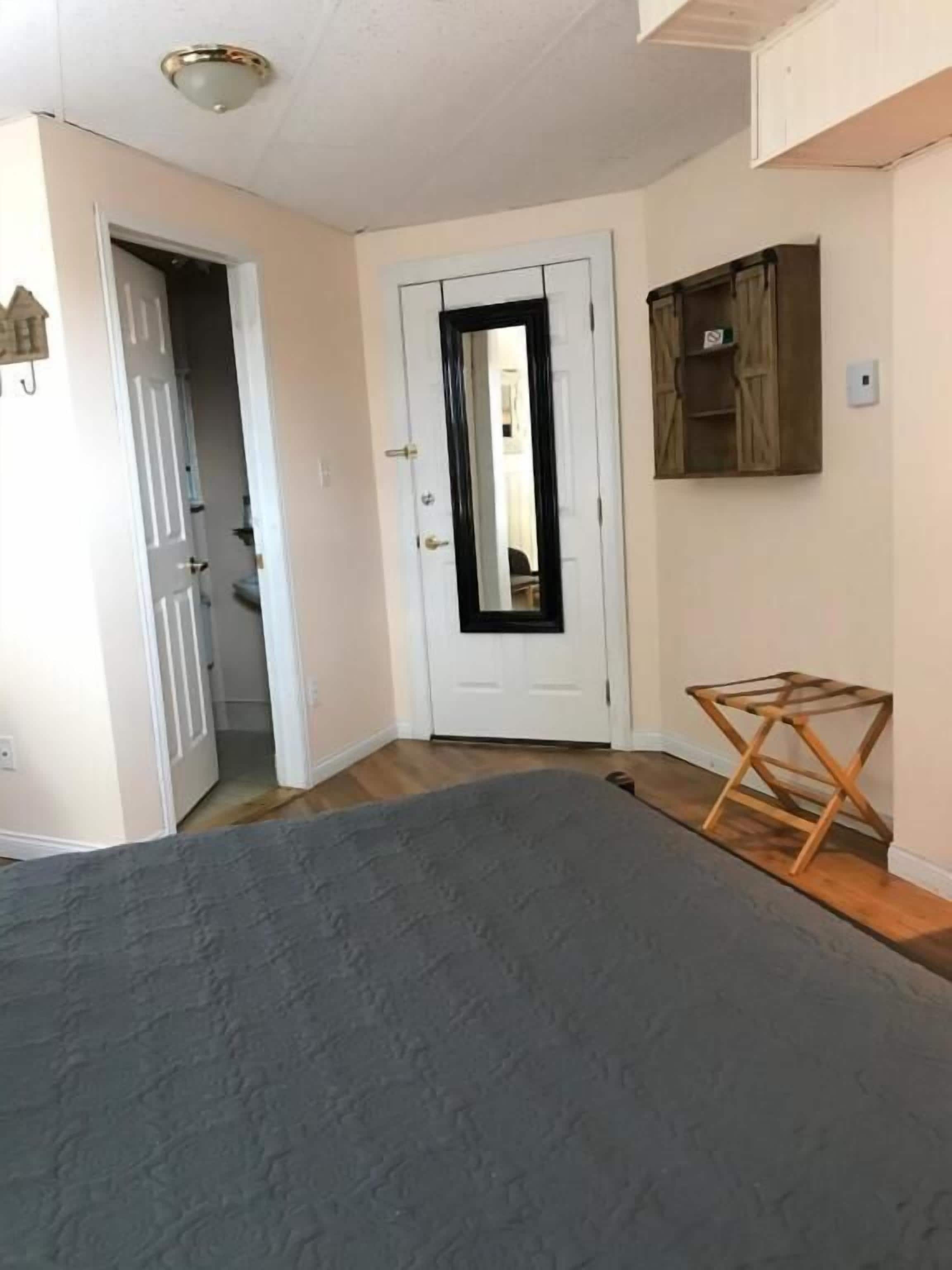 Une chambre avec un grand lit, un plancher en bois, une porte blanche et une petite table en bois.