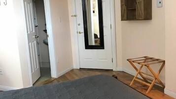 Une chambre avec un grand lit, un plancher en bois, une porte blanche et une petite table en bois.