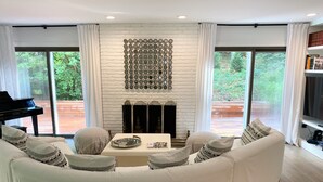 A modern living room with a white sectional sofa, a fireplace, and a piano. - Newly renovated Modern East Hampton Home / September available (East Hampton)