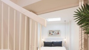 Ein Schlafzimmer mit einem Bett, einer weißen Treppe und einer Pflanze.