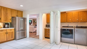 A modern kitchen with wooden cabinets, stainless steel appliances, and a tiled floor.