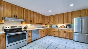Une cuisine moderne avec des meubles en bois, des appareils électroménagers en acier inoxydable et un sol carrelé.