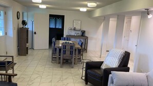 Amplia sala de estar con comedor, sofá, mesa de centro y una silla.