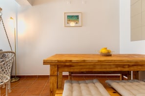 A wooden dining table with cushioned benches, a framed artwork on the wall, and a basket with lemons on the table.