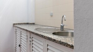 A kitchen with a granite countertop, stainless steel sink, and white cabinets. - Sweet 2-Bedroom Townhouse (Lagos)