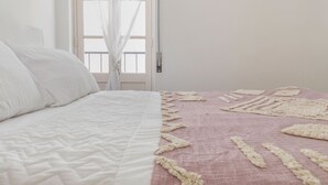 A bed with a white quilt and a pink blanket with a textured pattern. - Sweet 2-Bedroom Townhouse (Lagos)