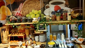 Een ontbijtbuffet met diverse etenswaren, zoals brood, gebak, fruit en drankjes.