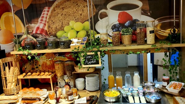 Een ontbijtbuffet met diverse etenswaren, zoals brood, gebak, fruit en drankjes.