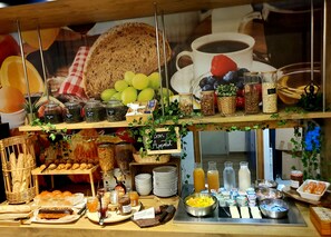 Un buffet de petit-déjeuner proposant une variété d’aliments, notamment du pain, des viennoiseries, des fruits et des boissons.