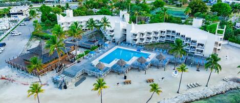 A resort with a large pool, beach area, and multiple buildings.