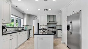 A modern kitchen with white cabinetry, a stainless steel refrigerator, and a central island. - Heated Pool 3BR Home · 4 Min to Hollywood Beach (Hollywood)
