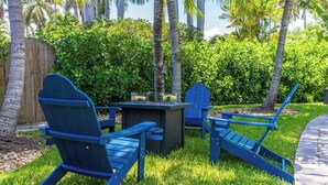 A patio area with blue Adirondack chairs, a small table, and a grill. - Heated Pool 3BR Home · 4 Min to Hollywood Beach (Hollywood)