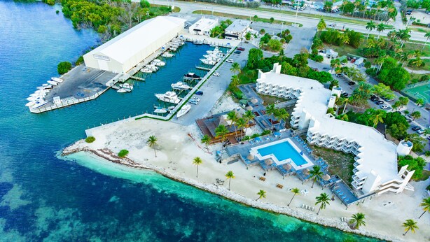 Vista aérea de un resort con un puerto deportivo, piscina y zona de playa.
