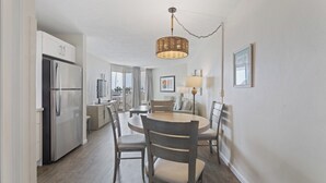Una cucina moderna con frigorifero integrato, un'area pranzo con tavolo e sedie rotonde, e una lampada a sospensione.