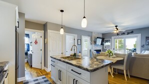 A modern kitchen with white cabinets, a granite countertop, and pendant lighting. - SSVR4-Downtown Munising Apartment, 2 blocks from Lake Superior (Munising)