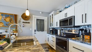 A modern kitchen with white cabinets, stainless steel appliances, and a marble countertop. - SSVR4-Downtown Munising Apartment, 2 blocks from Lake Superior (Munising)