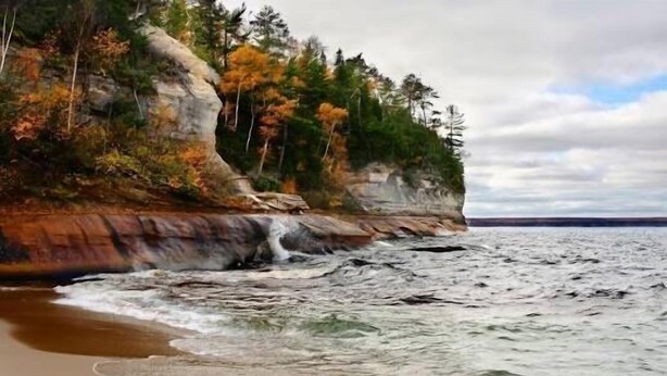 A coastal landscape with a rocky cliff and a beach. - SSVR4-Downtown Munising Apartment, 2 blocks from Lake Superior (Munising)