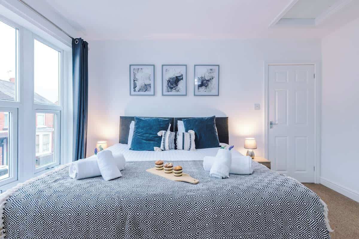 A hotel room with a large bed, a view of the city, and three framed artworks on the wall.