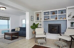 Cozy up by the fireplace in this inviting living room with ocean views and a comfortable seating area.