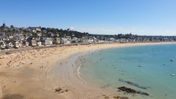 Une ville côtière dotée d’une vaste plage de sable, d’eaux bleues et limpides, et d’immeubles résidentiels qui bordent la côte.