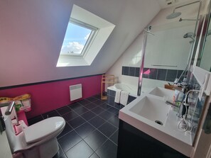 Et moderne badeværelse med ovenlys, badekar, bruser og toilet.