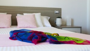 Un lit bien fait, avec une couverture rose et une écharpe colorée posée dessus.