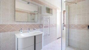 Une salle de bain moderne avec un grand lavabo, un miroir et une douche en verre.
