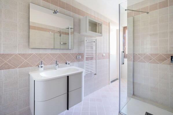 Une salle de bain moderne avec un grand lavabo, un miroir et une douche en verre.