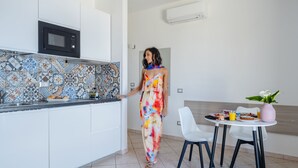 Une cuisine moderne avec des meubles blancs, un pare-feu décoré et un coin repas comprenant une table et des chaises blanches.