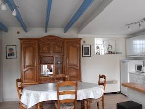 Un comedor con una mesa y sillas de madera, un armario y una zona de cocina con microondas.