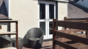 A balcony with wicker furniture and a white door. - 5 bedroom accommodation in New Quay (New Quay)