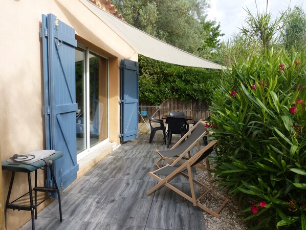 A patio with a table and chairs, a wooden deck, and a garden area with plants and flowers. - Studio in Bandol in a villa with a swimming pool (Bandol)