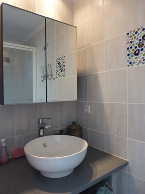 A bathroom with a white sink, a mirror above it, and a tiled wall with a decorative mosaic. - Studio in Bandol in a villa with a swimming pool (Bandol)