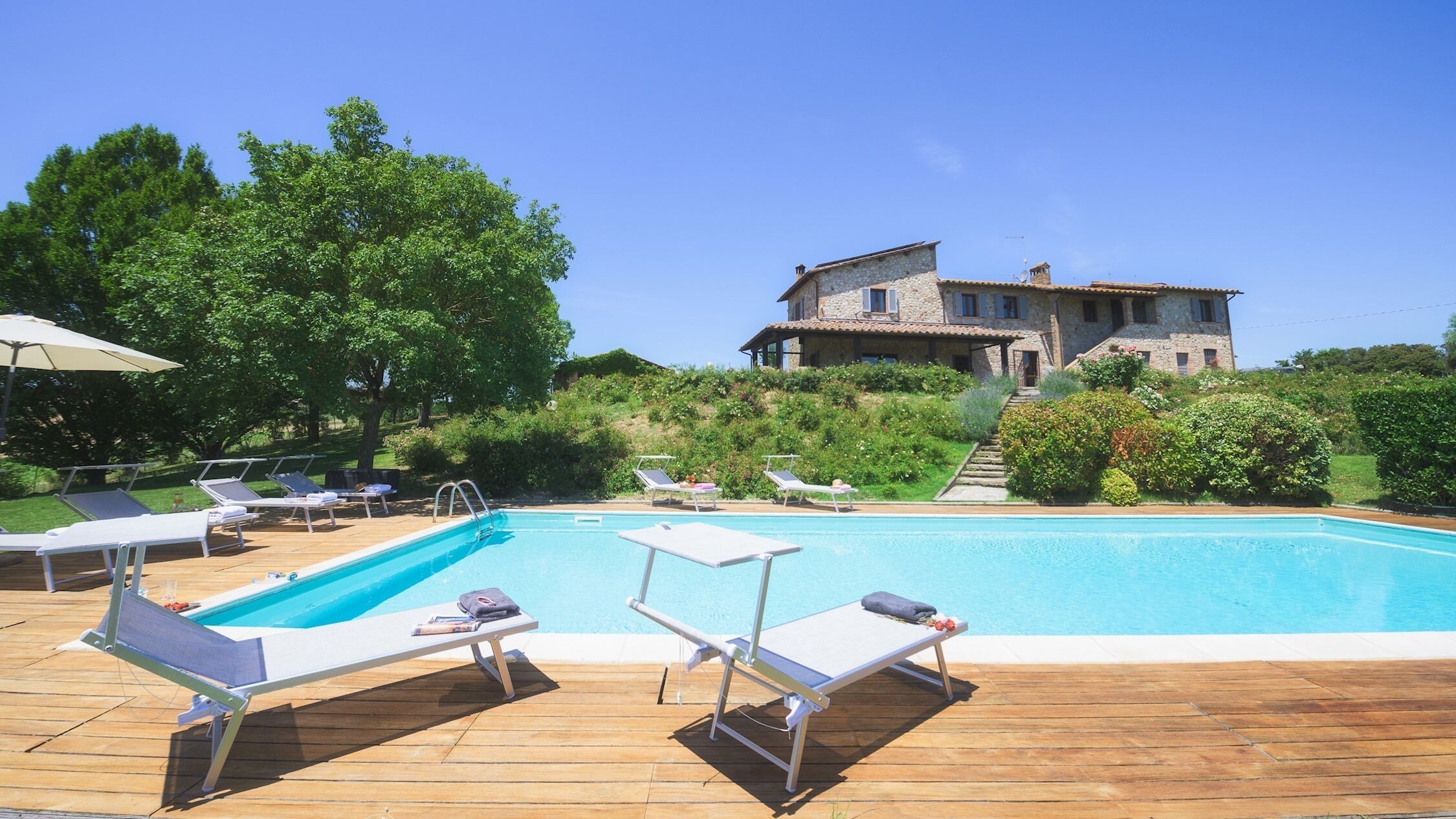 A pool area with lounge chairs and a stone building in the background.