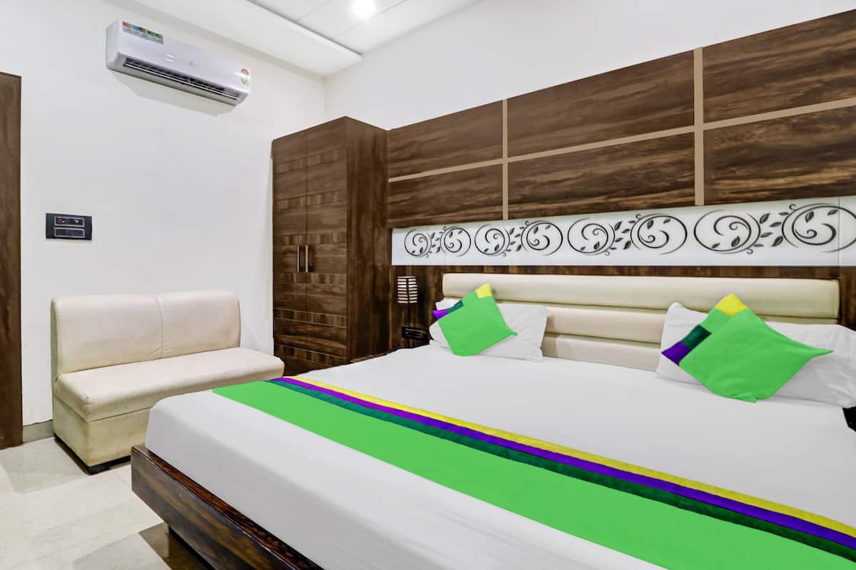 Un dormitorio con cama, un banco, armario de madera y unidad de aire acondicionado.