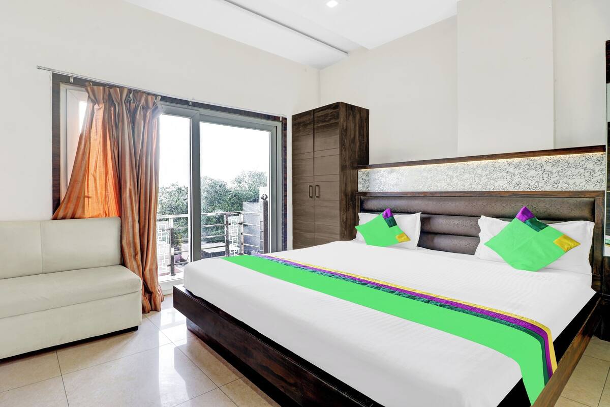 Habitación de hotel con cama, sofá, armario y vistas al exterior.